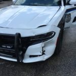 A white police car with the front end of it's bumper smashed.