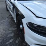 A white police car with the front end of it's door broken.