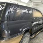 A black suv is being painted in the shop.