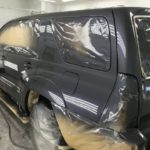 A black suv is being painted with some kind of paint.